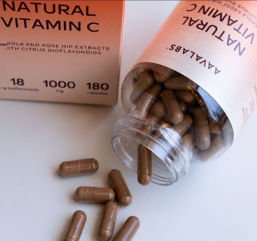 Flacone rovesciato con capsule marroni e capsule sparse accanto.