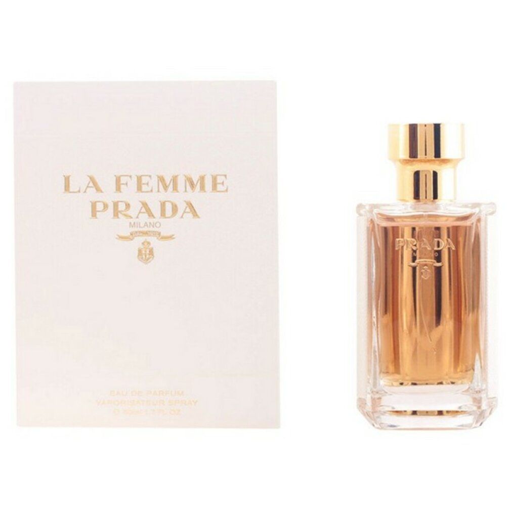 Flacone di profumo accanto a confezione bianca. Sulla confezione 'La Femme Prada'. Flacone con tappo dorato.