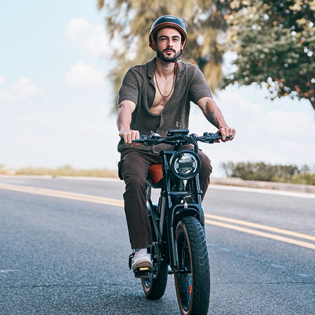 Uomo in sella a una bicicletta elettrica nera. Indossa un casco e una camicia.