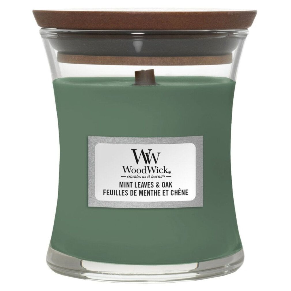 Candela verde a forma di clessidra con coperchio in legno. Etichetta con nome del prodotto e marchio WoodWick. Mint Leaves & Oak.