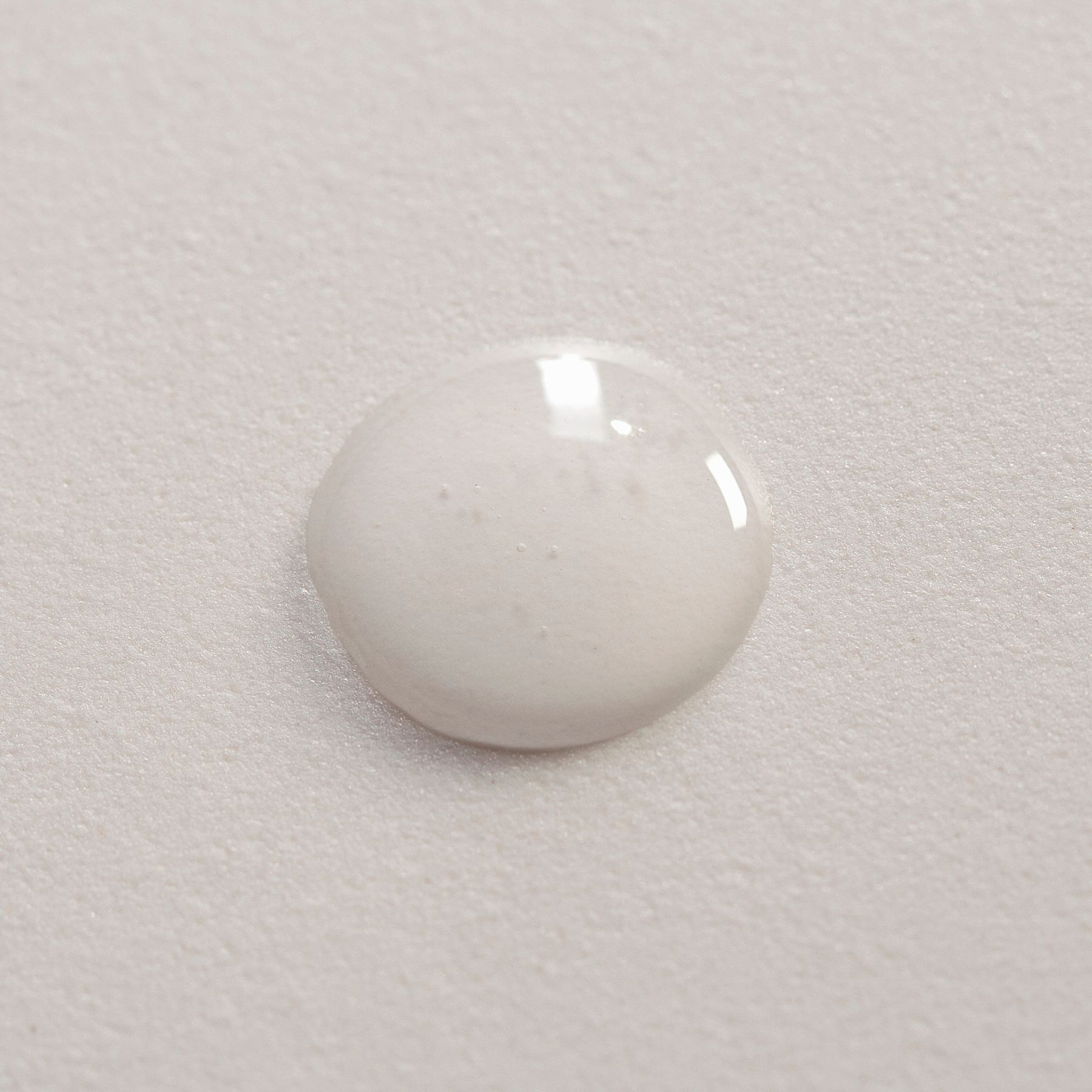 Una goccia di siero bianco su una superficie testurizzata.