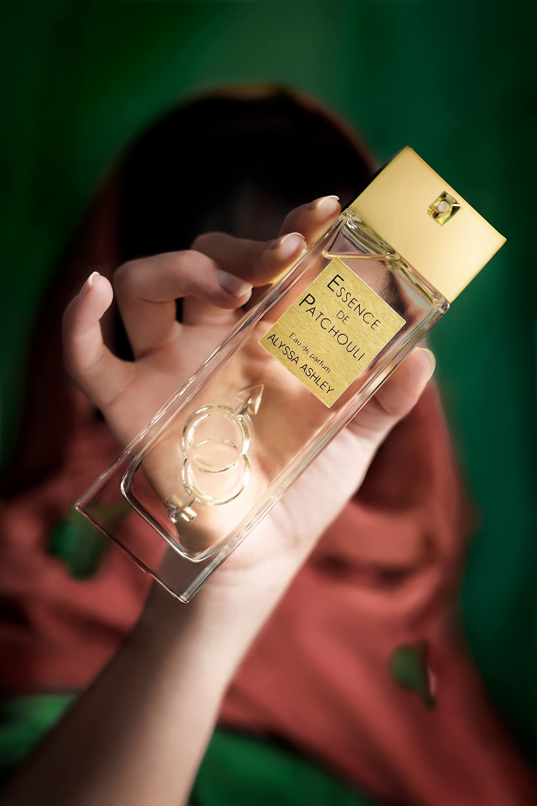 Mano che tiene un flacone Alyssa Ashley Essence de Patchouli Eau de Parfum.