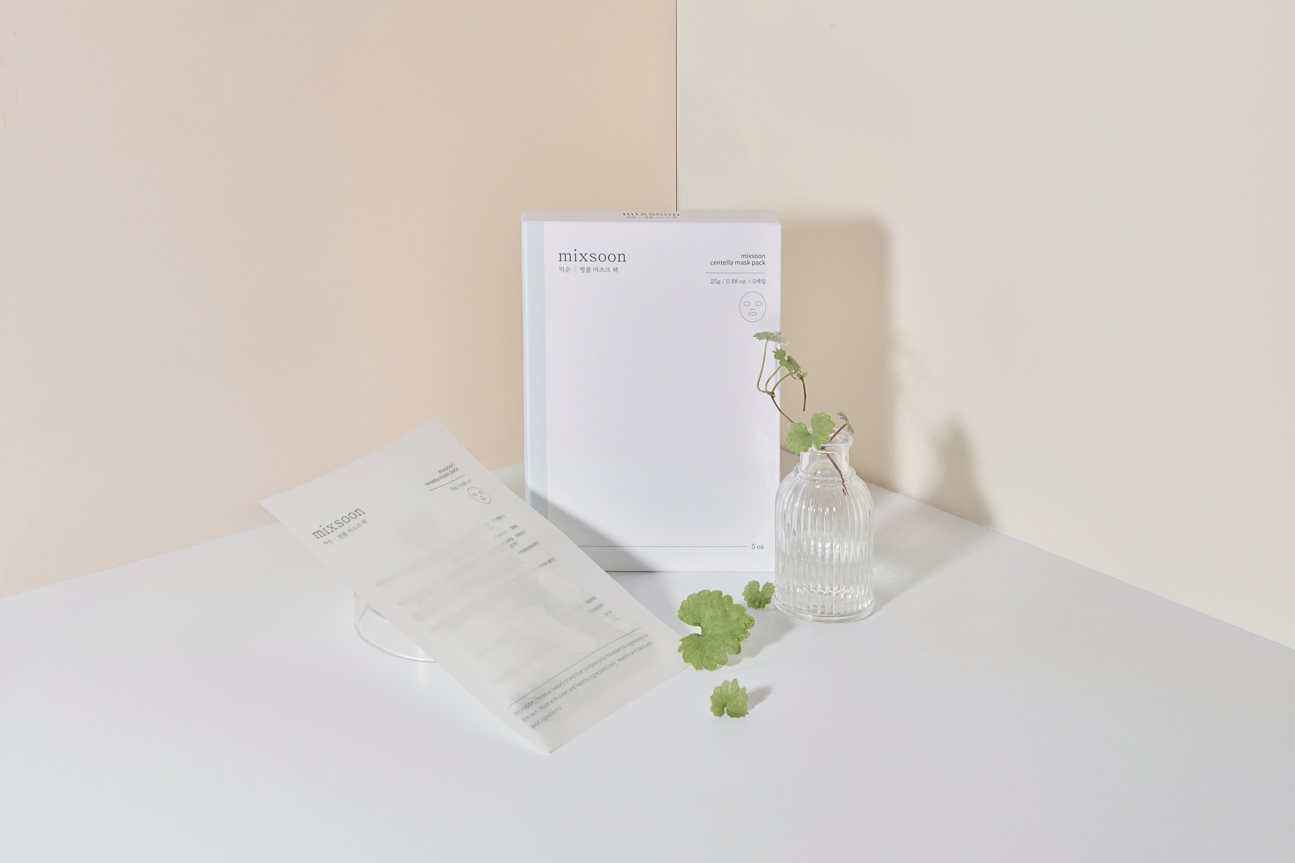 Confezione Mixsoon Centella Mask Pack. Pacco bianco rettangolare. Accanto, vaso trasparente con foglie verdi.