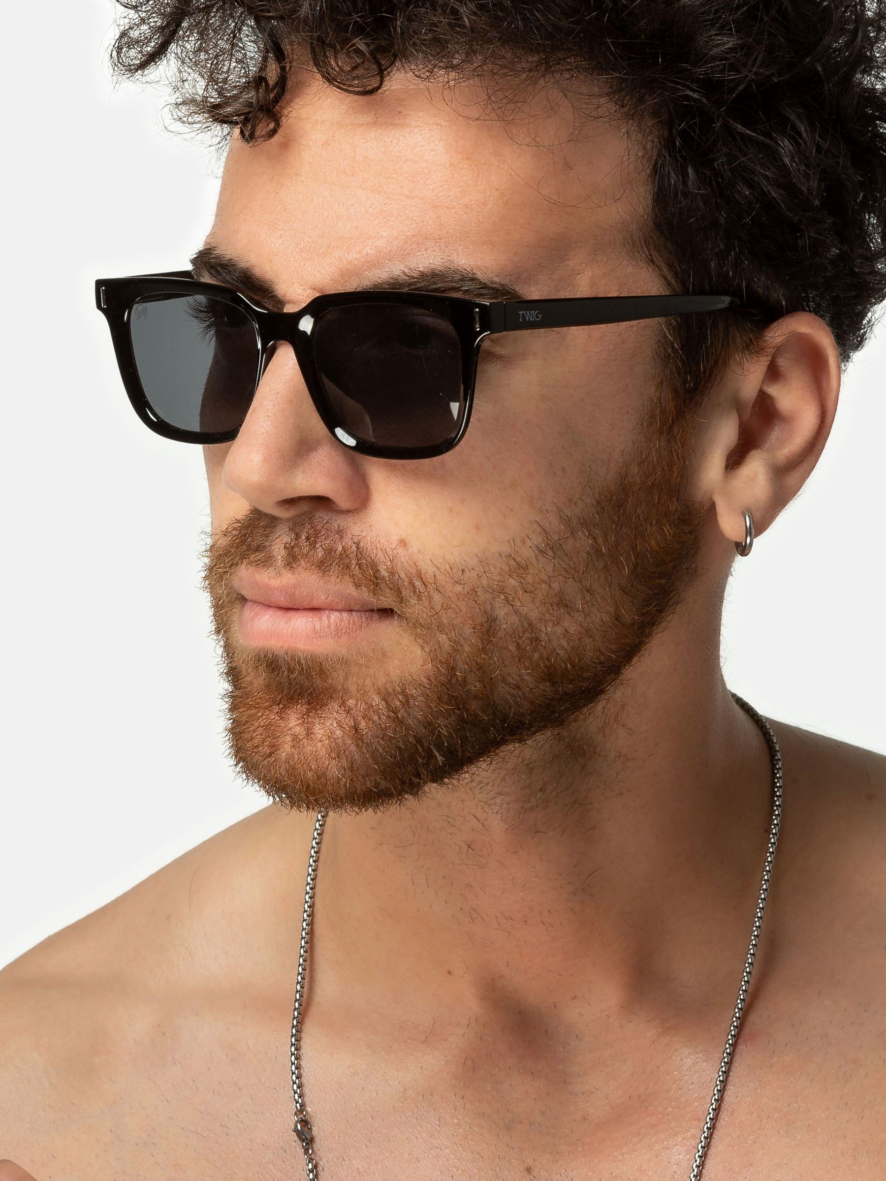 Uomo con occhiali da sole Twig. Montatura nera, lenti rettangolari. Primo piano.