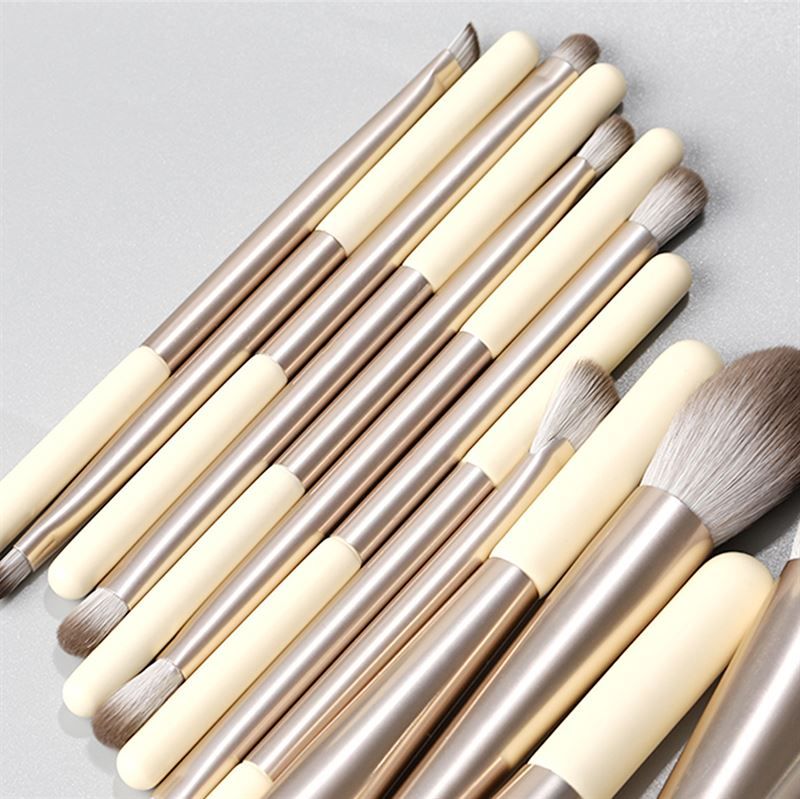 Set di pennelli per trucco. 12 pennelli con manici color crema, ghiera argentata e diverse testine.