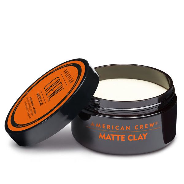 Barattolo nero con coperchio arancione. Sul coperchio è scritto "AMERICAN CREW MATTE CLAY". Il barattolo è aperto.