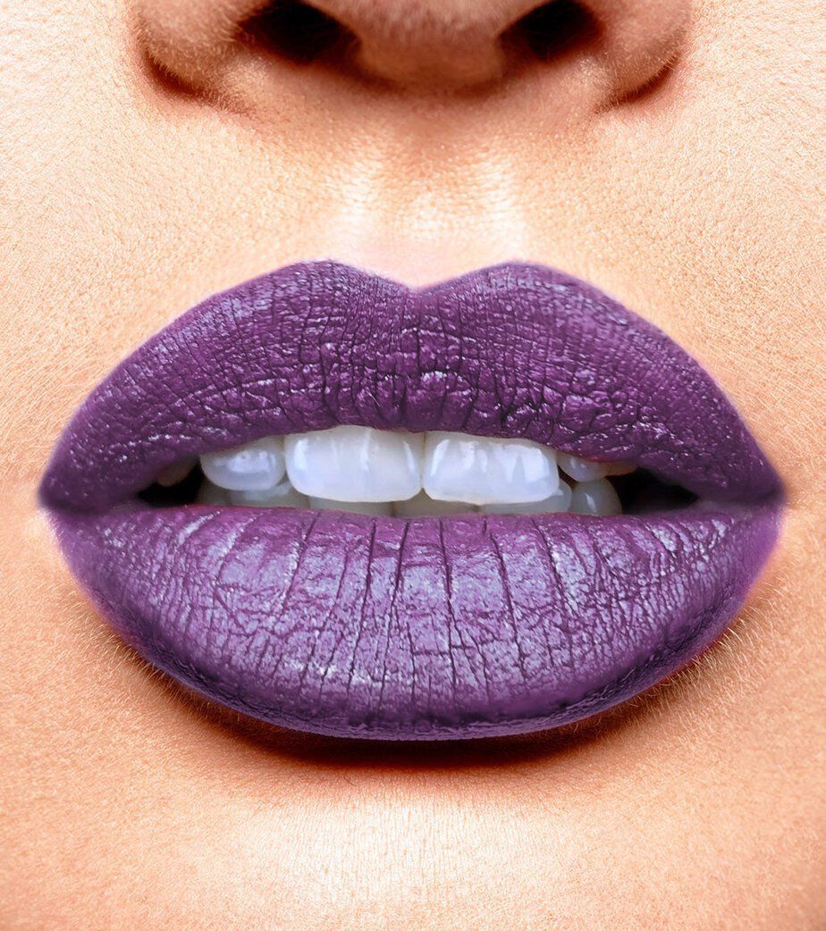 Labbra con rossetto opaco viola. Denti visibili.