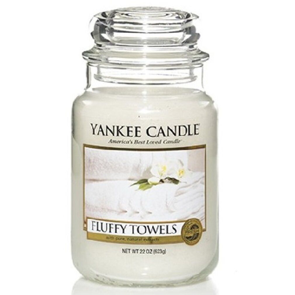 Candela profumata Fluffy Towels di Yankee Candle. Contenitore in vetro con coperchio. Etichetta con asciugamani e fiori. Netto 22 oz (623g).