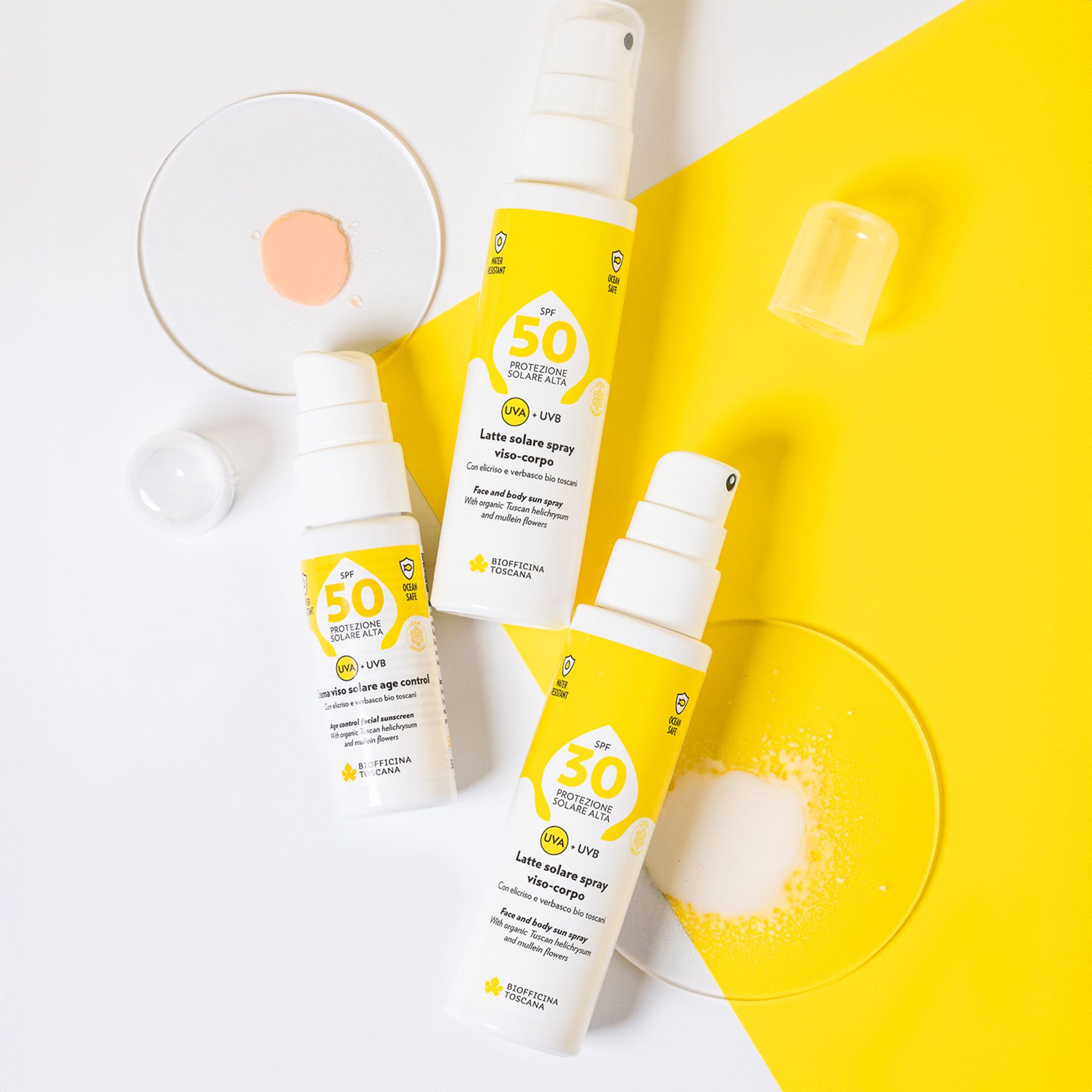Tre flaconi spray bianchi con etichette gialle. Testo: SPF 50, SPF 30, protezione solare, UVA+UVB. Marchio: Biofficina Toscana. Su sfondo giallo.