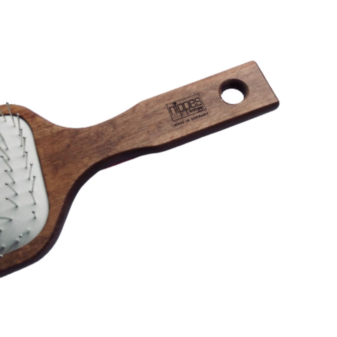 Dettaglio della spazzola per capelli. Manico in legno con foro. Marchio Nippes, Made in Germany. Setole metalliche.