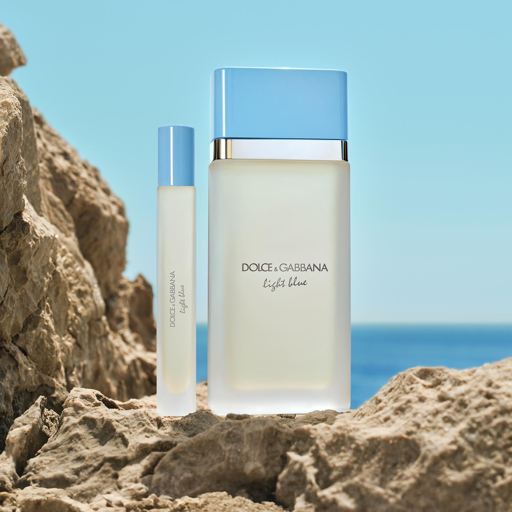 Flacone e roll-on su pietra. Sfondo: mare e rocce. Scritta: Dolce & Gabbana Light Blue.