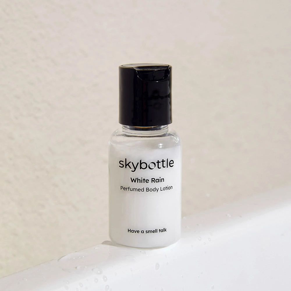 Flacone di lozione per il corpo, bianco, tappo nero. Scritta: SKYBOTTLE White Rain Parfümierte Körperlotion.