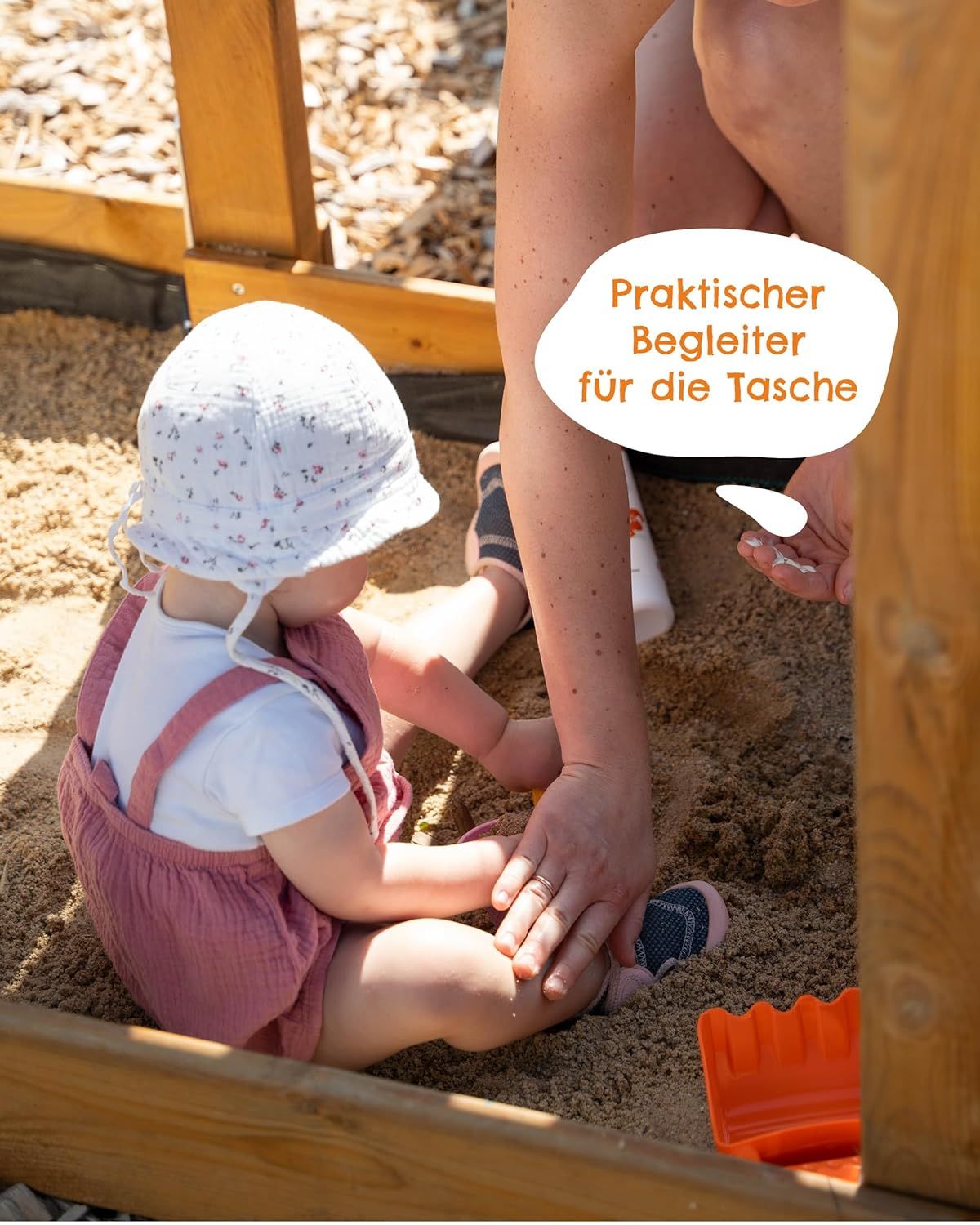 Bambino in una sabbiera, assistito da una persona. Il bambino indossa un cappello e una tuta. Testo: Compagno pratico per la borsa.