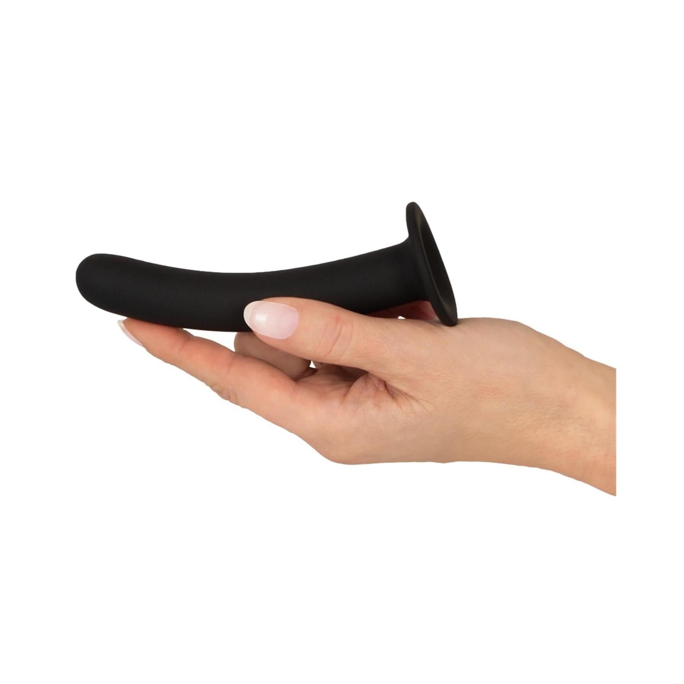 Dildo anale nero in una mano. Curvo, con base a ventosa. Silicone. Superficie morbida. Sfondo bianco.