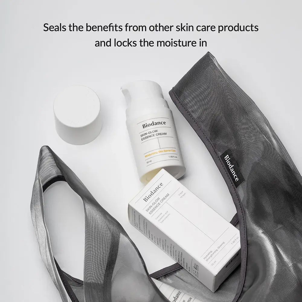 Flacone e confezione del prodotto in una borsa a rete. Testo: Biodance Skin-Glow Essence Cream. Sigilla i benefici.