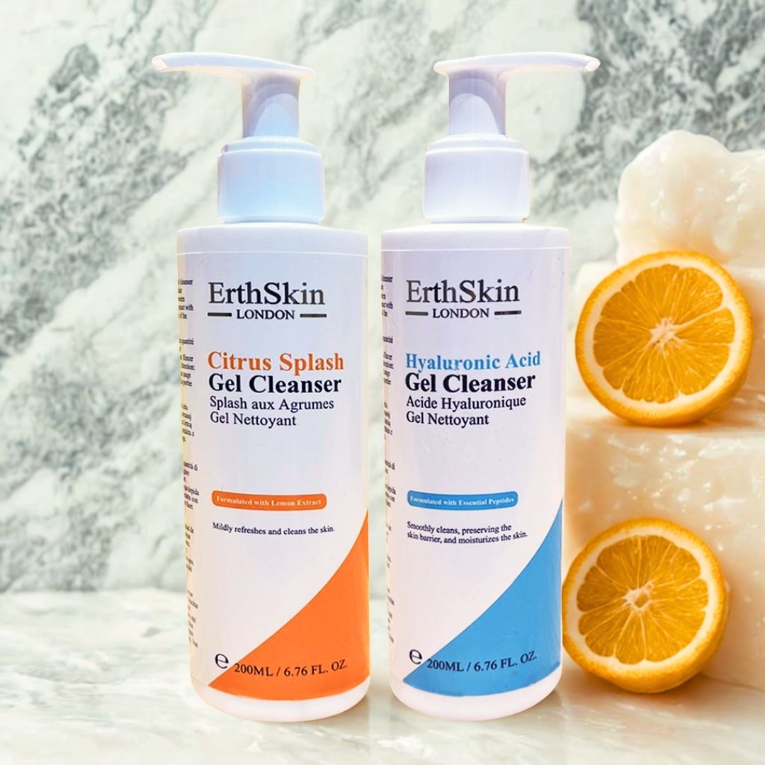 Due flaconi di gel detergente ErthSkin London. Flacone arancione con "Citrus Splash", blu con "Acido Ialuronico". Fette di arancia accanto.