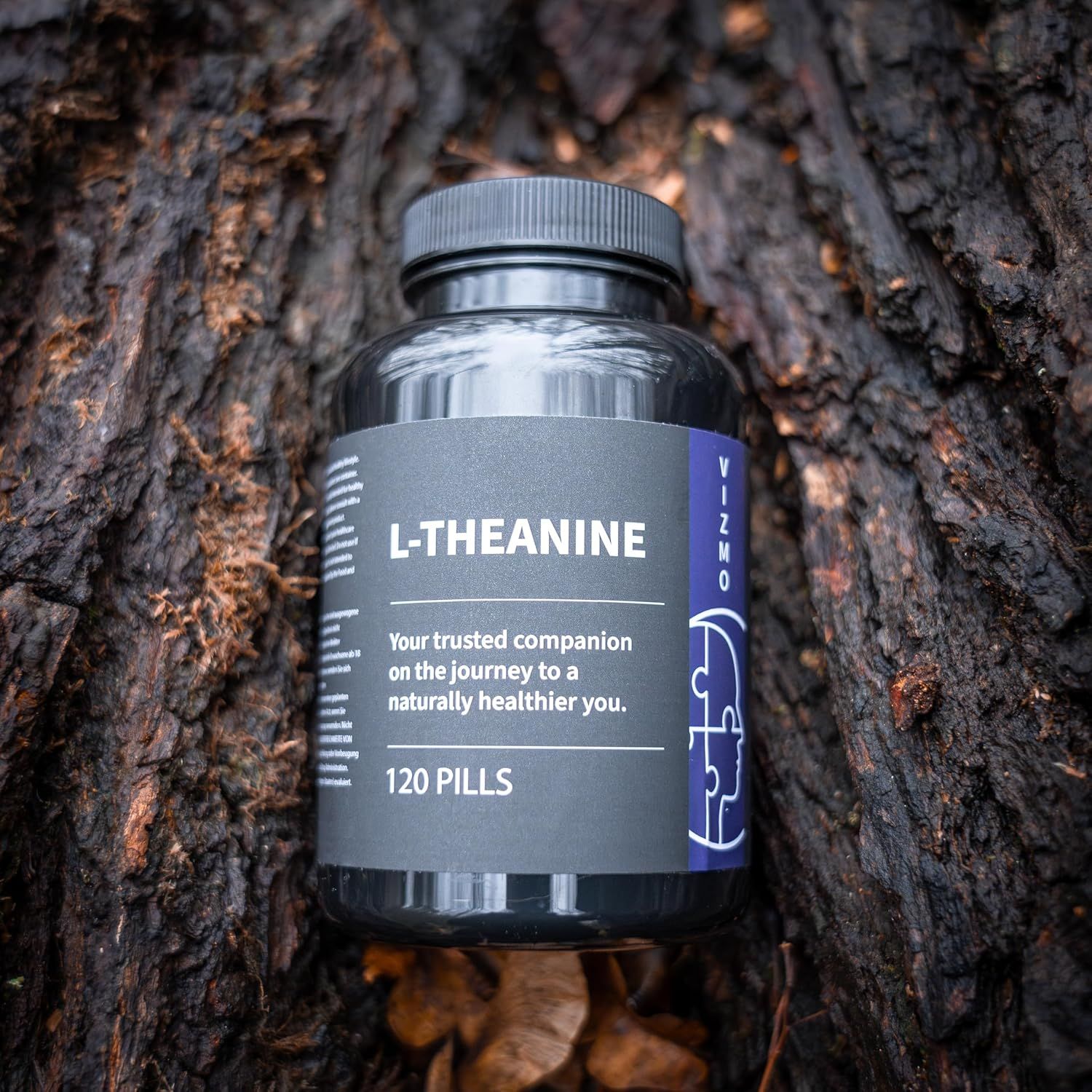 Flacone nero di capsule Vizmo L-Teanina. 120 pillole. Posizionato sulla corteccia.