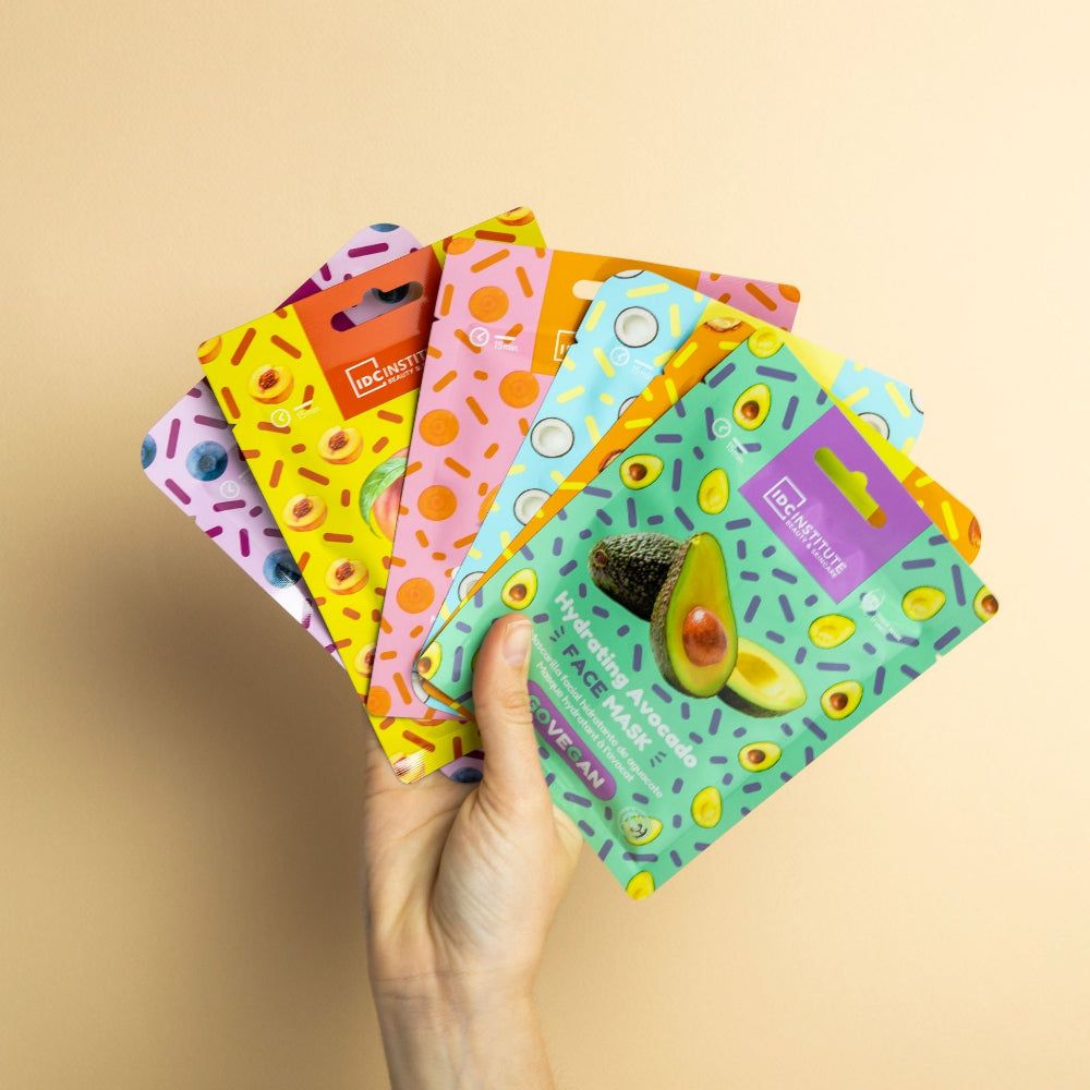 Più maschere viso colorate. Mano che tiene le maschere. Marchio: IDC Institute. Vegano.
