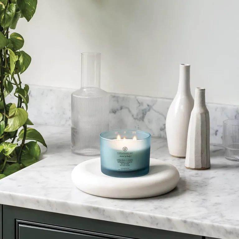Candela blu Chesapeake Bay, mind & body, reflection + clarity, su piedistallo bianco. Decorazione con vasi.