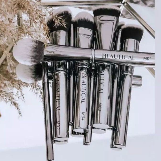 Set di pennelli con manici argentati. Il marchio BEAUTICAL è visibile. Su uno specchio.