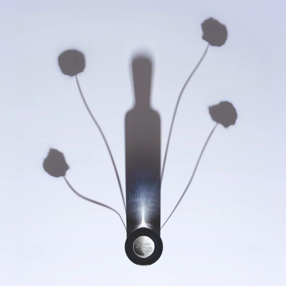 Ombra di un flacone di profumo con fiori. Scritta: Juliette has a gun, Musc Invisible.