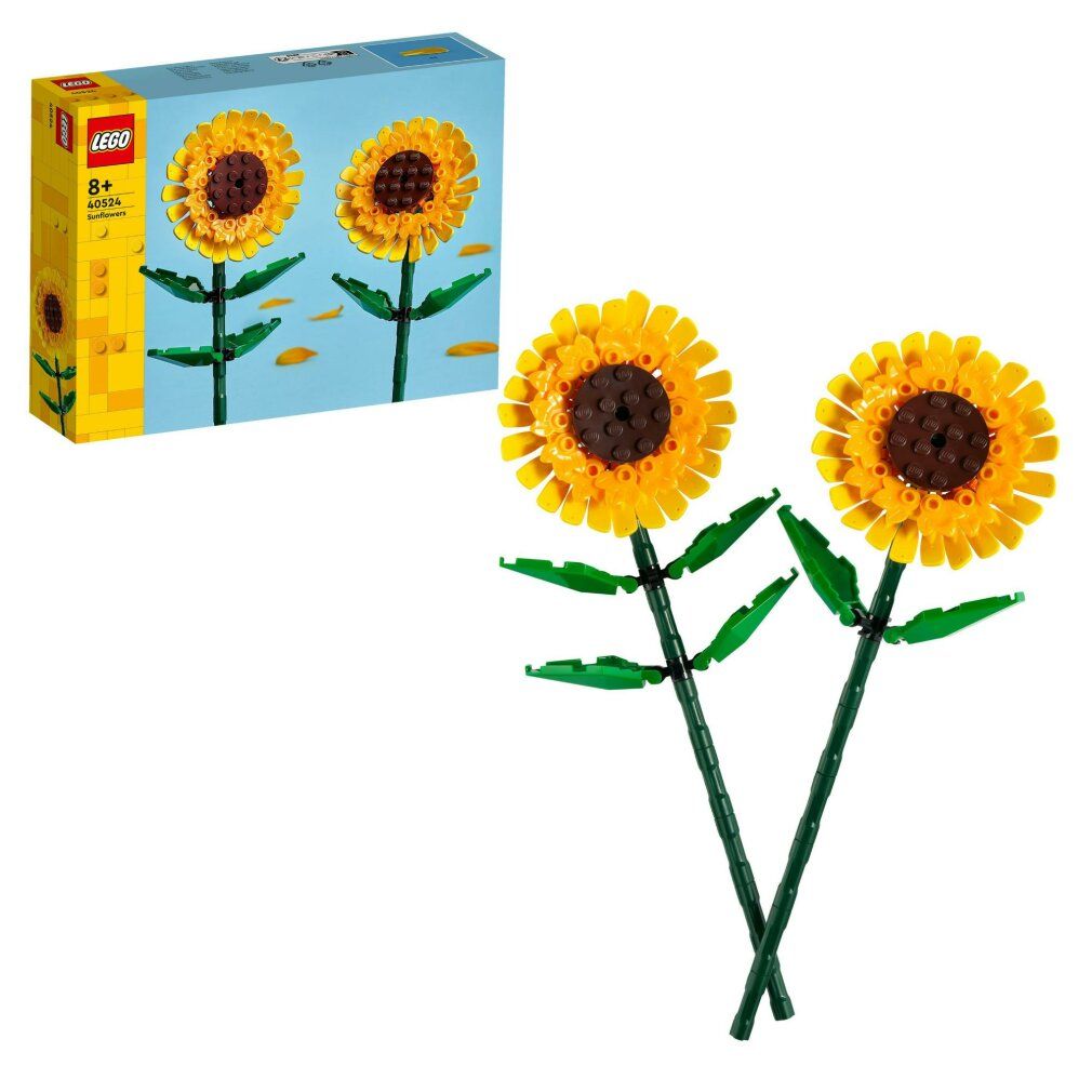 Due girasoli fatti con mattoncini LEGO. Petali gialli, centro marrone, steli e foglie verdi. Confezione LEGO sullo sfondo.