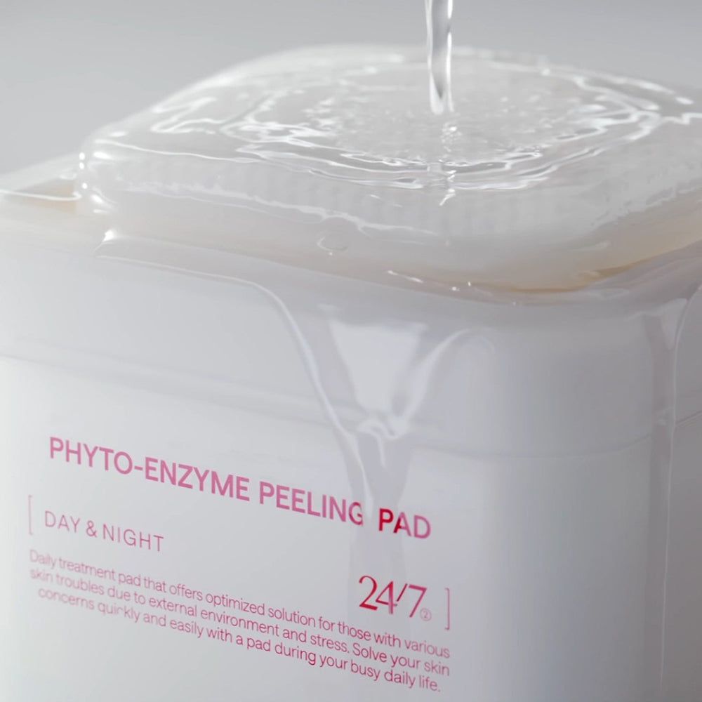 Primo piano di un contenitore bianco con "PHYTO-ENZYME PEELING PAD". Liquido versato sui pad.