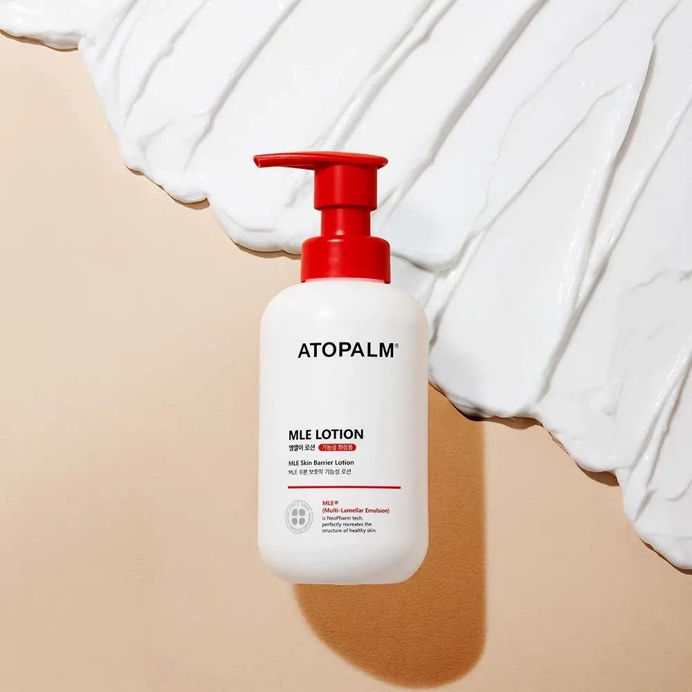 Flacone bianco con erogatore rosso. Scritta: ATOPALM MLE LOTION. Crema su sfondo bianco.