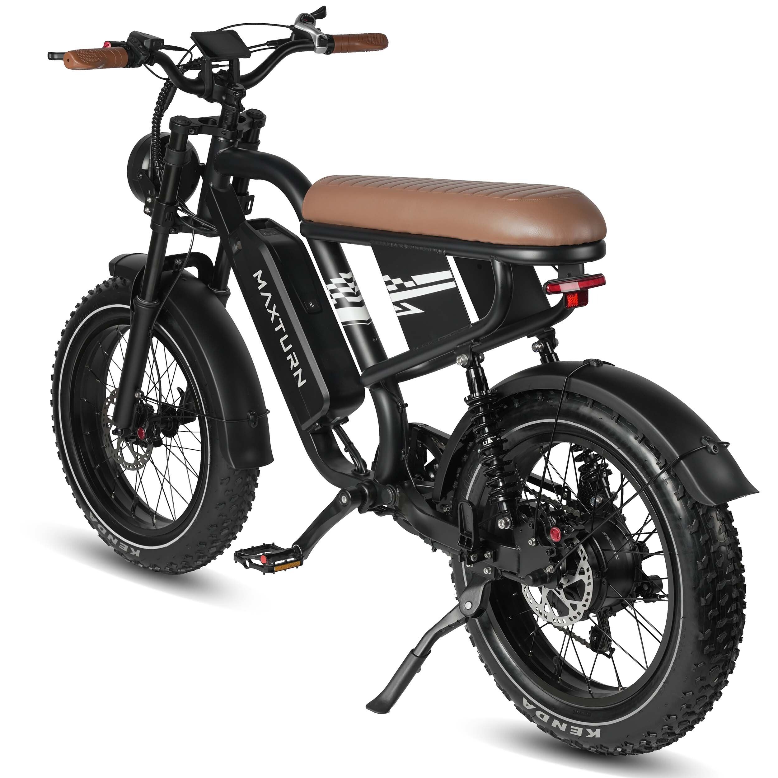 E-bike nera con sella marrone. Scritta "MAXTURN" sul telaio. Pneumatici larghi e cavalletto.