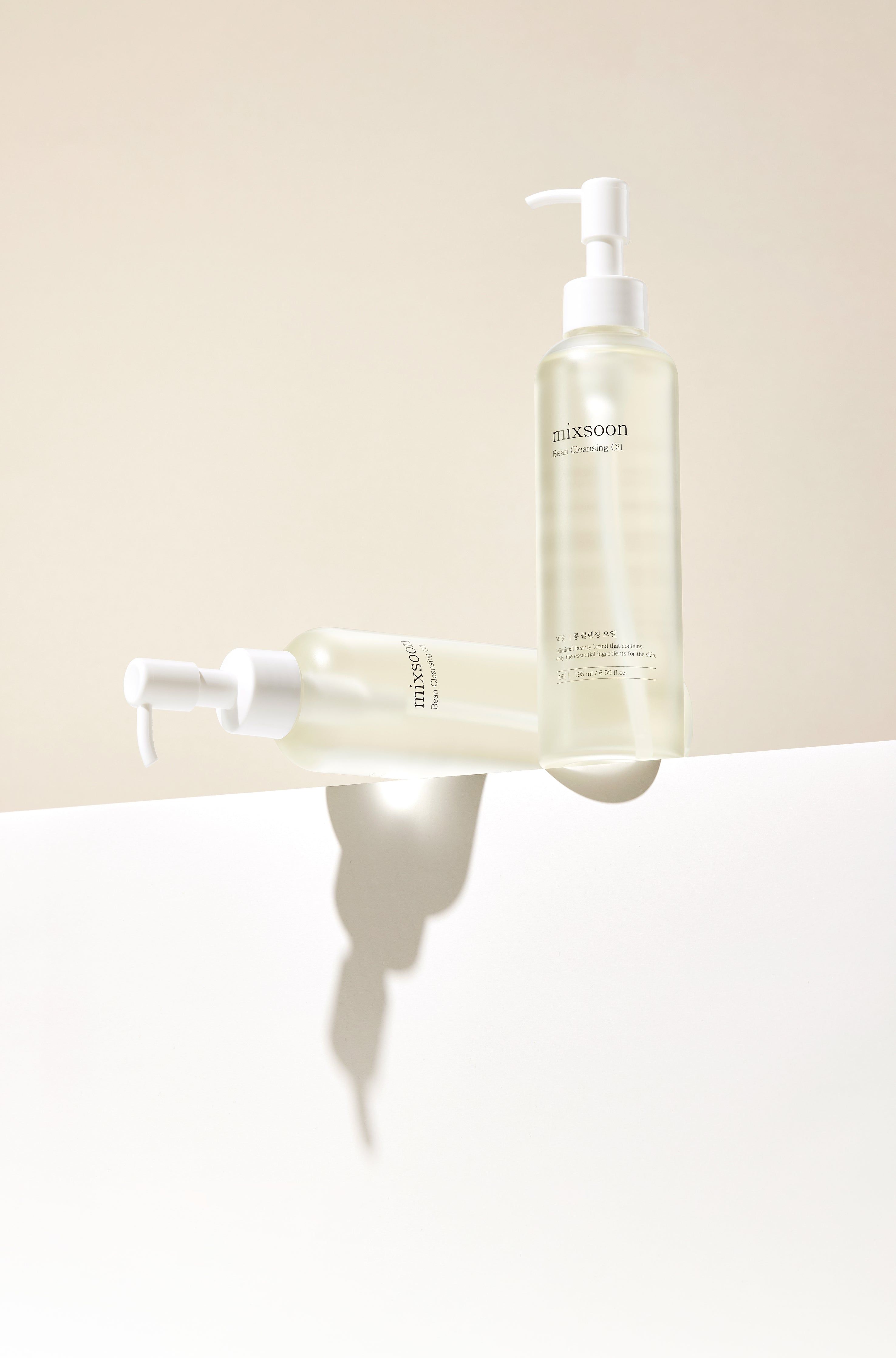 Due flaconi di olio detergente mixsoon Bean su una superficie bianca con ombra.