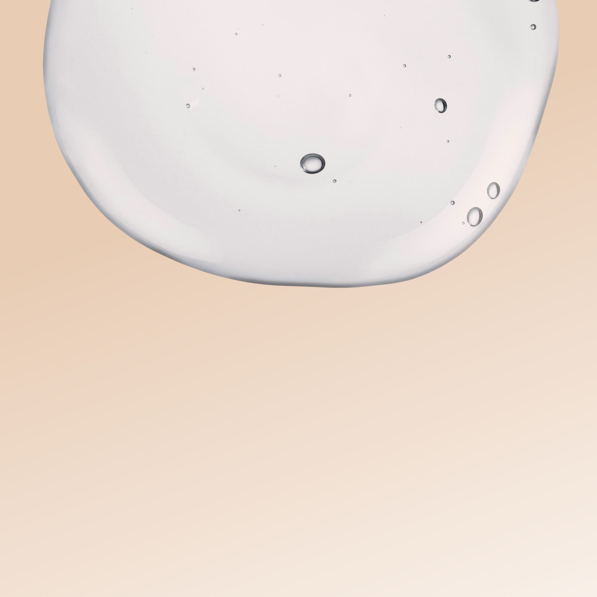 Primo piano di una goccia di gel trasparente. Bolle visibili nel gel. Sfondo: beige.