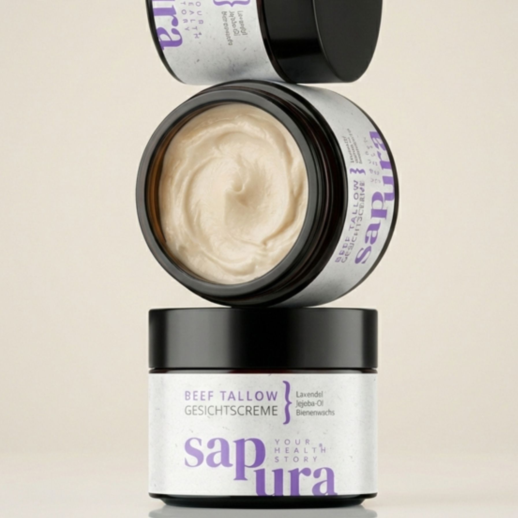 Tre vasetti di crema impilati. Scritta: BEEF TALLOW GESICHTSCREME, Lavanda, Olio di jojoba, Cera d'api. Marchio: sapura.
