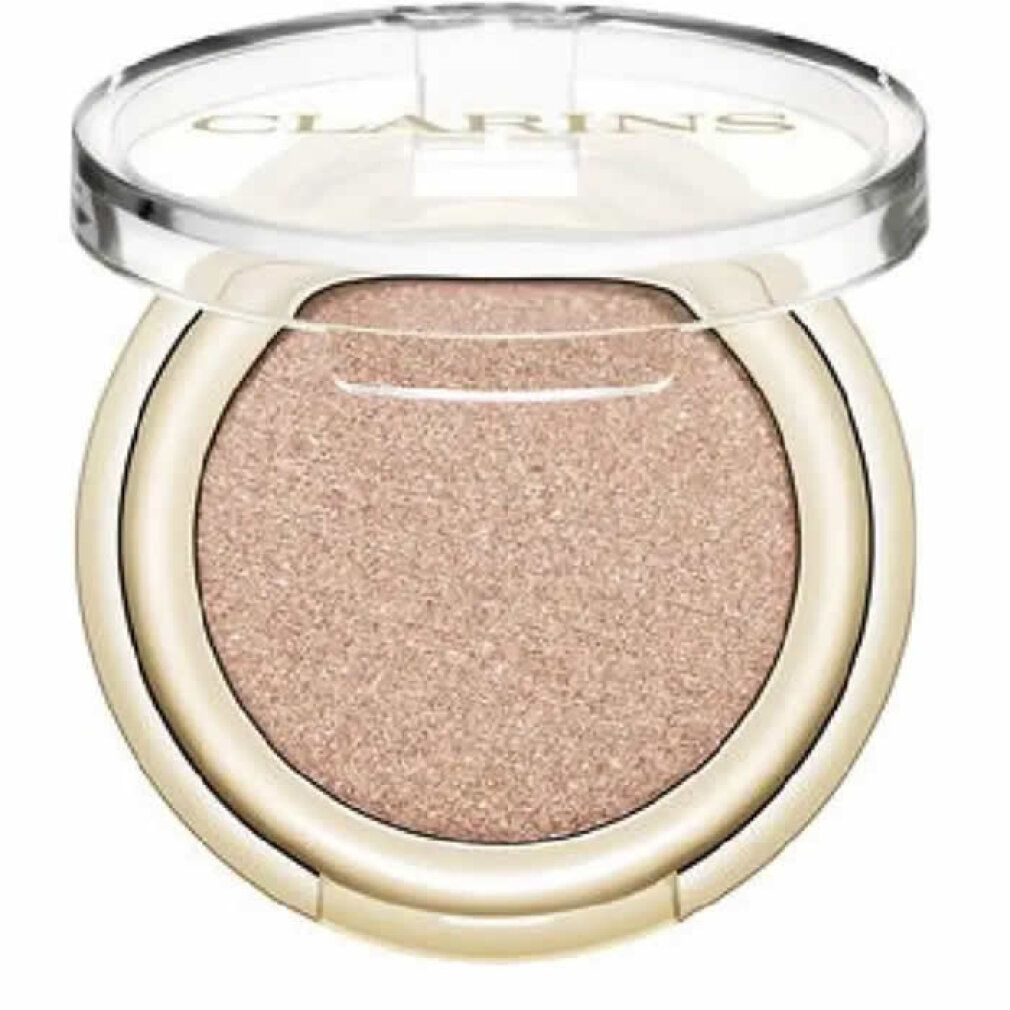 Contenitore rotondo dorato di ombretto con contenuto rosa. Il coperchio trasparente è aperto. Clarins è visibile.