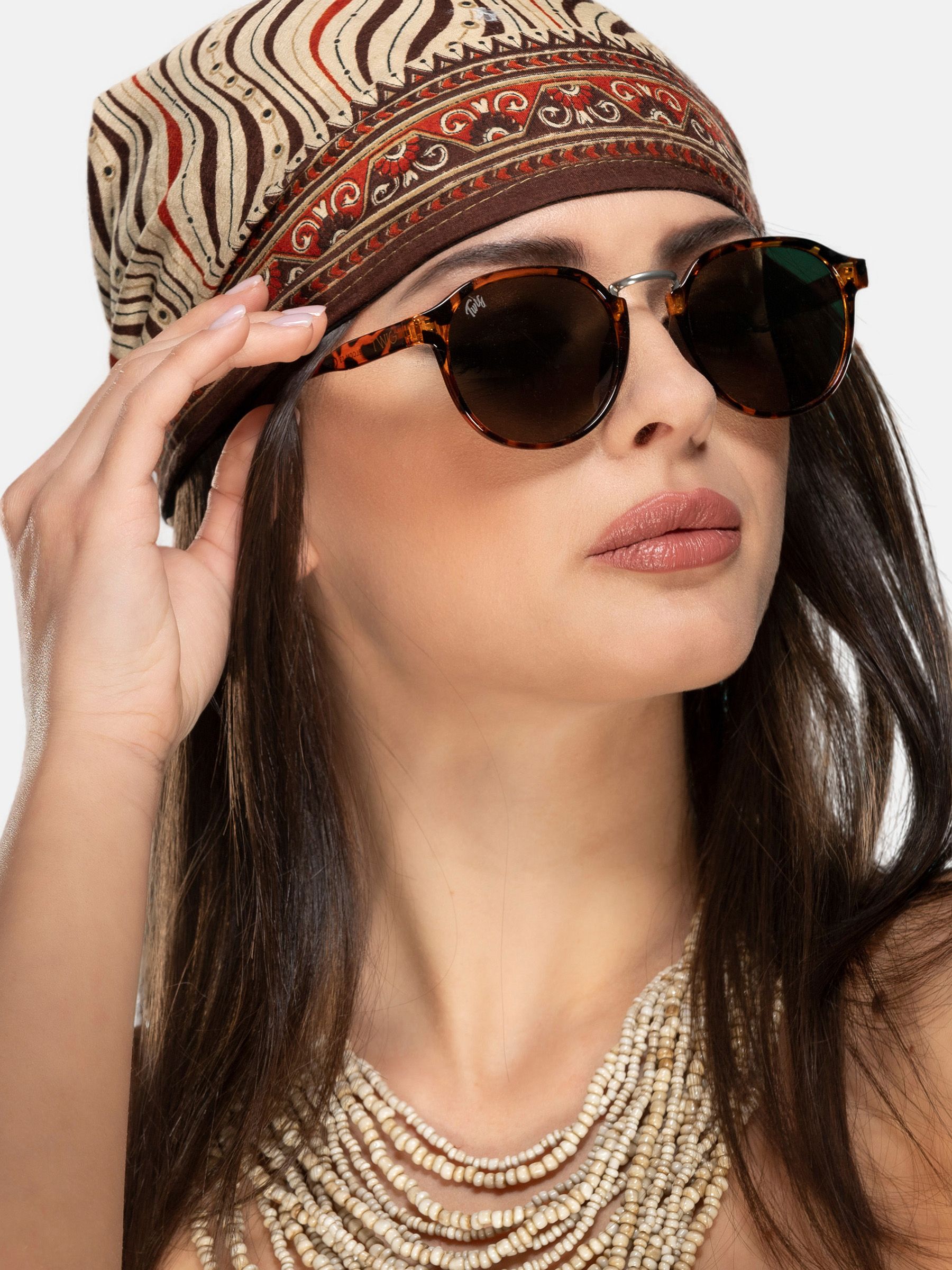 Donna con occhiali da sole rotondi marrone fantasia e foulard.