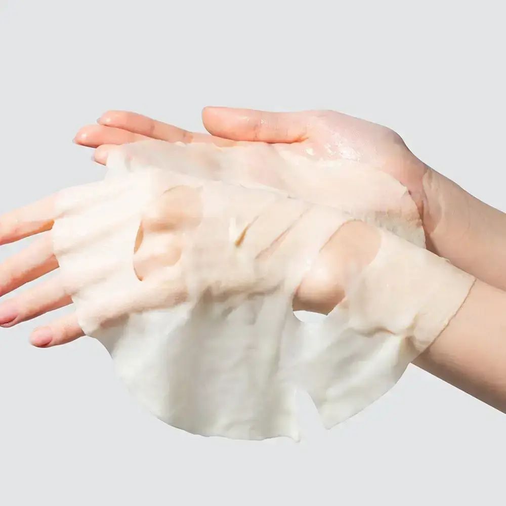 Maschera per il viso tra le mani. Fori per occhi, naso e bocca. Texture chiara e trasparente. Su sfondo chiaro.