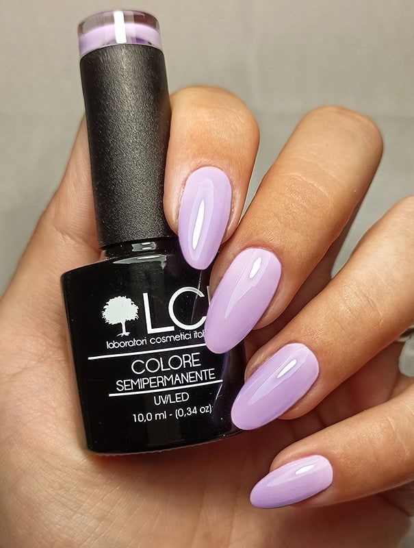 Mano con unghie smaltate e flacone smalto. Scritta: LCI, Colore Semipermanente, UVLED, tonalità lilla.