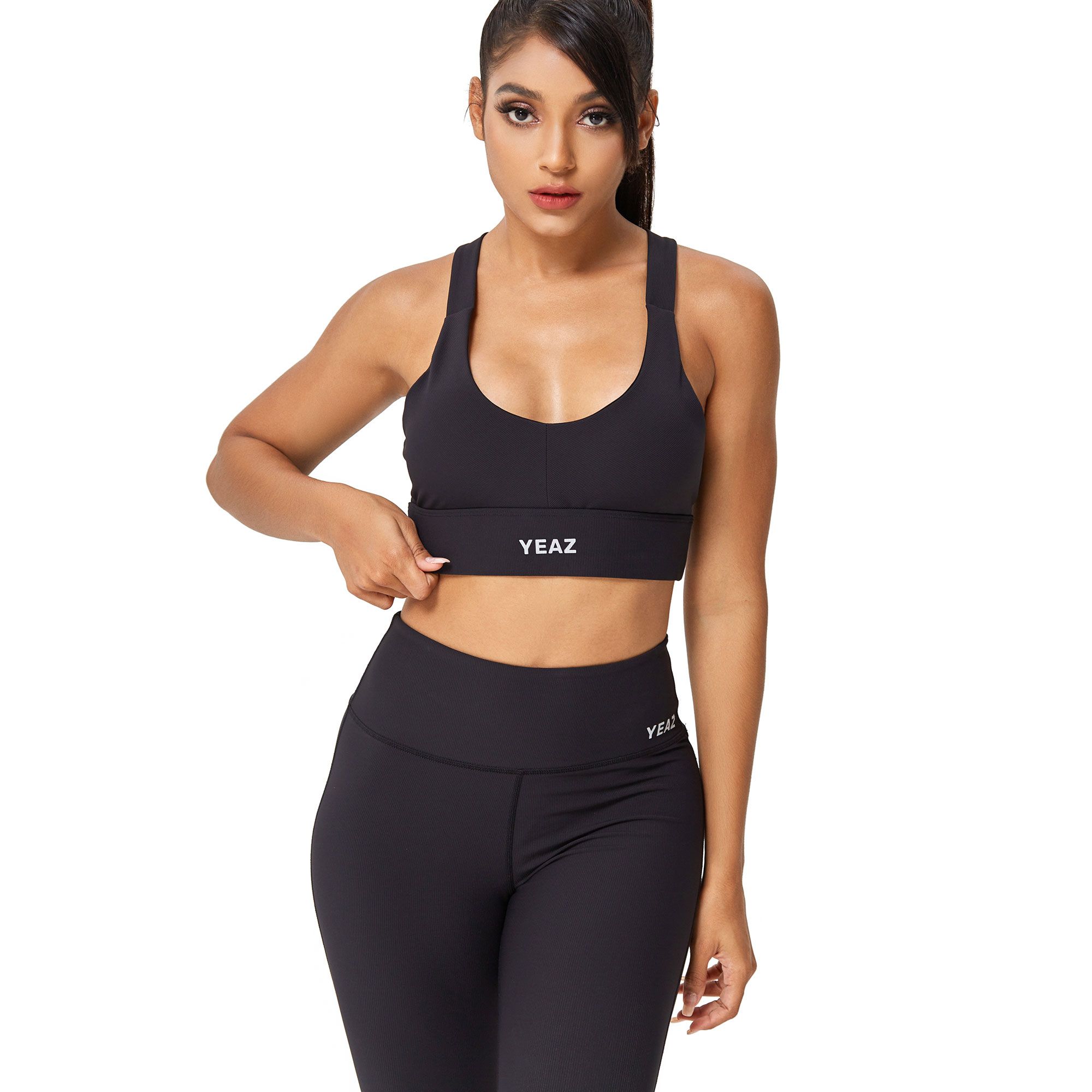 Reggiseno sportivo nero con fascia larga e logo YEAZ, abbinato a leggings.