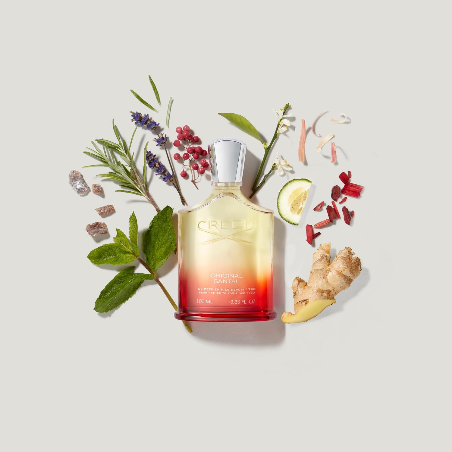 Flacone di profumo circondato da erbe e spezie. Scritta: CREED ORIGINAL SANTAL.