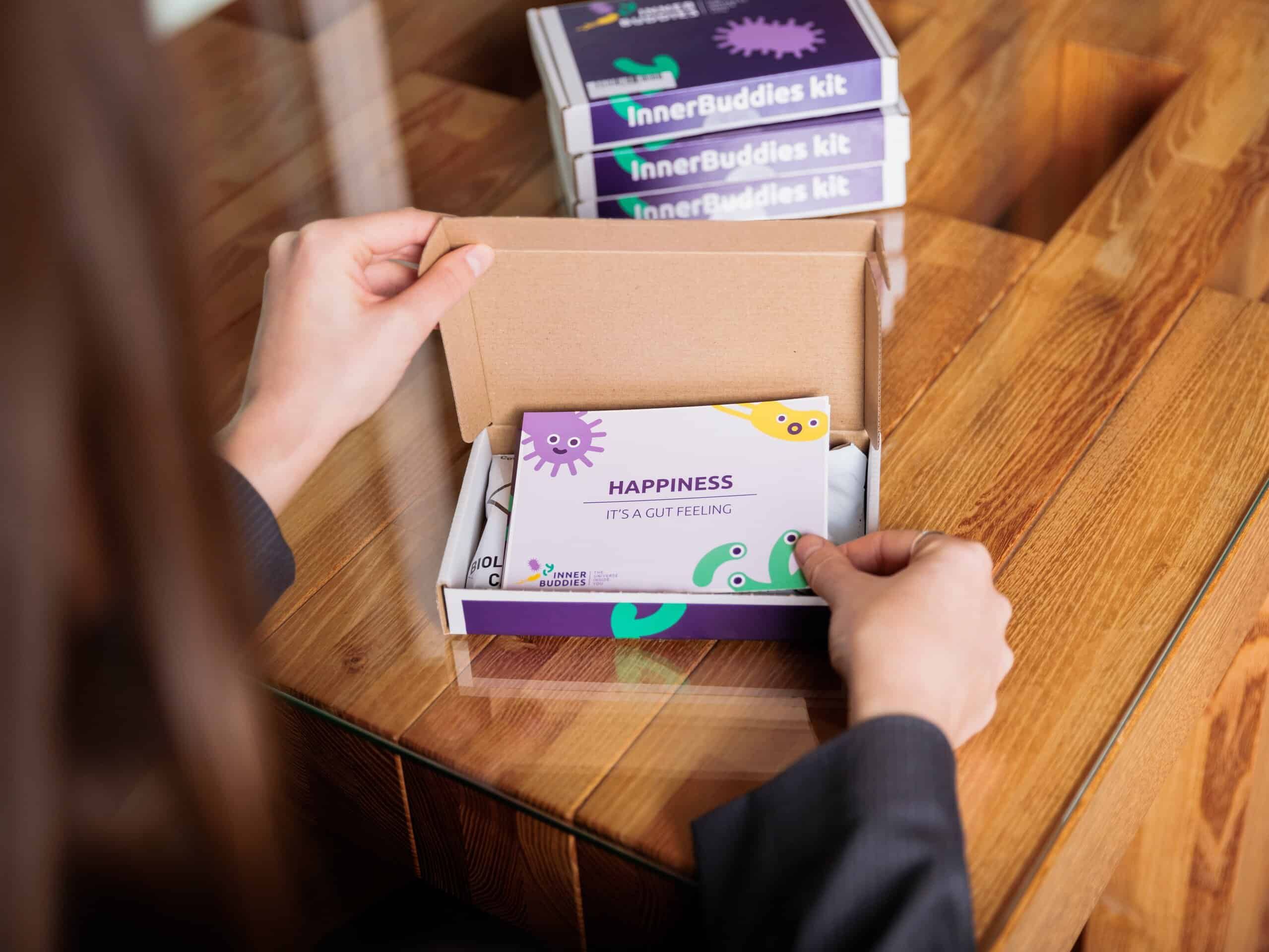 Persona che apre una confezione di kit di test Inner Buddies, rivelandone il contenuto.