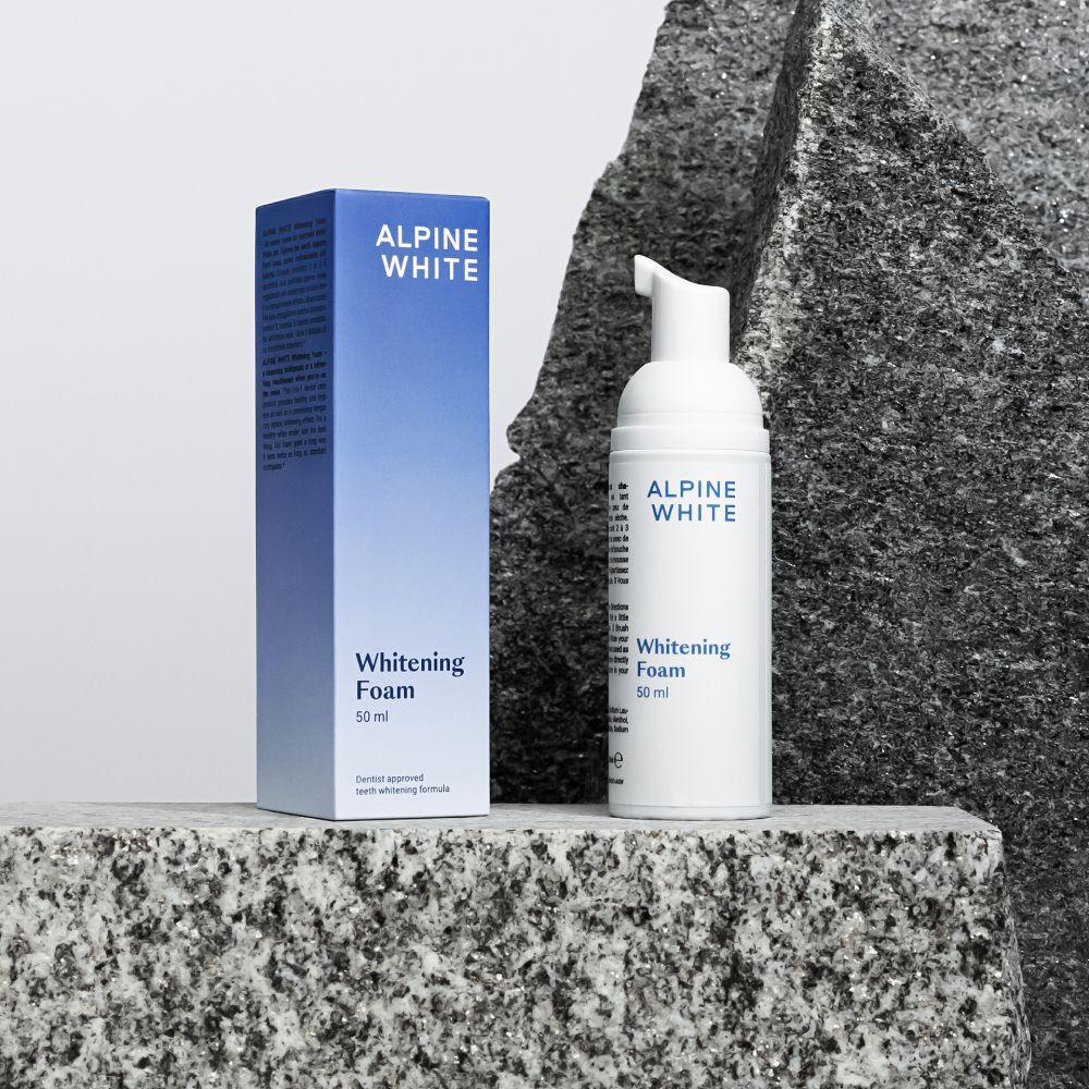 Flacone e scatola bianchi con "ALPINE WHITE Whitening Foam". Su pietra. 50 ml.