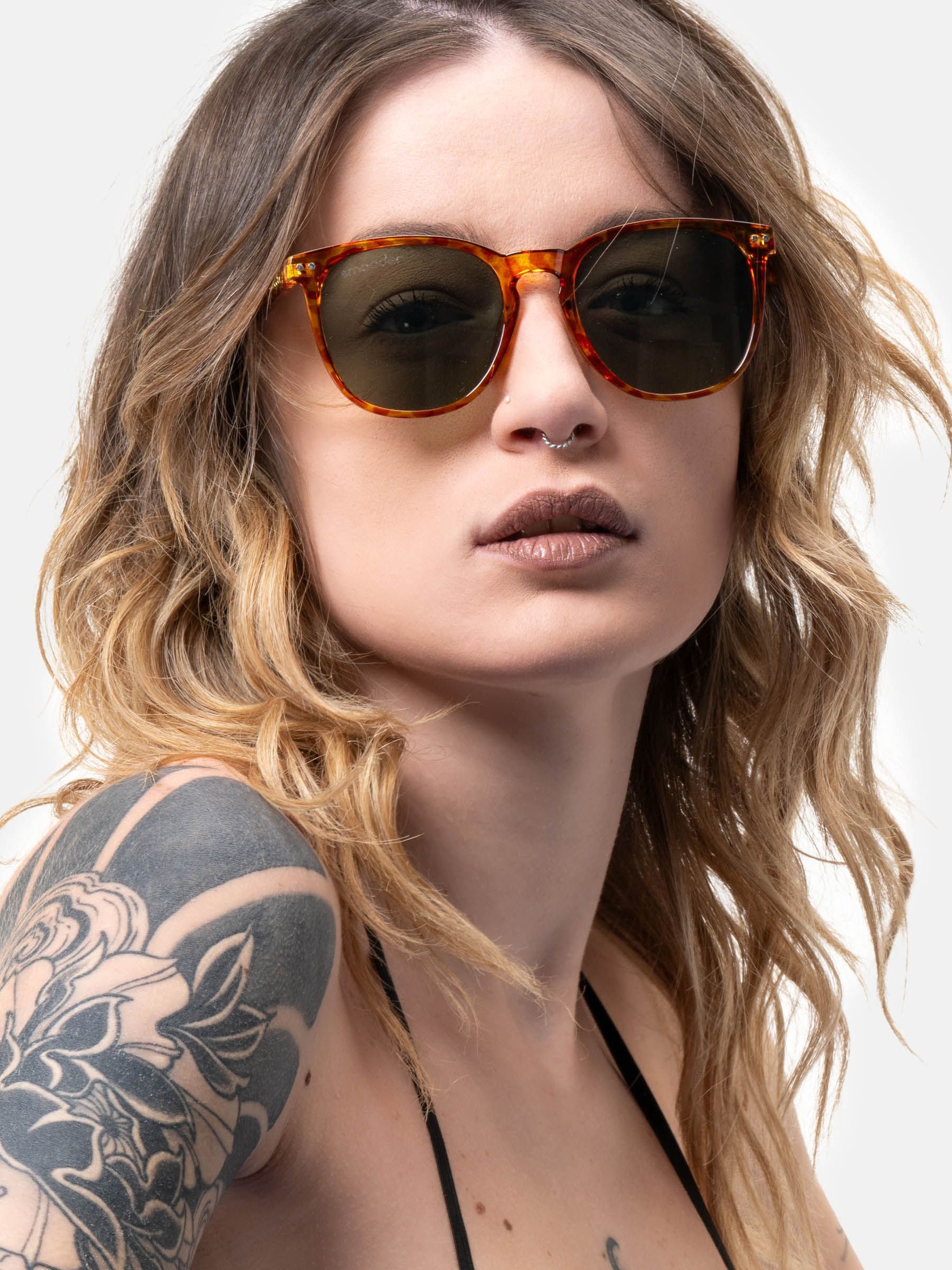 Donna con occhiali da sole con montatura marrone-gialla e lenti verdi. Gli occhiali coprono gli occhi.