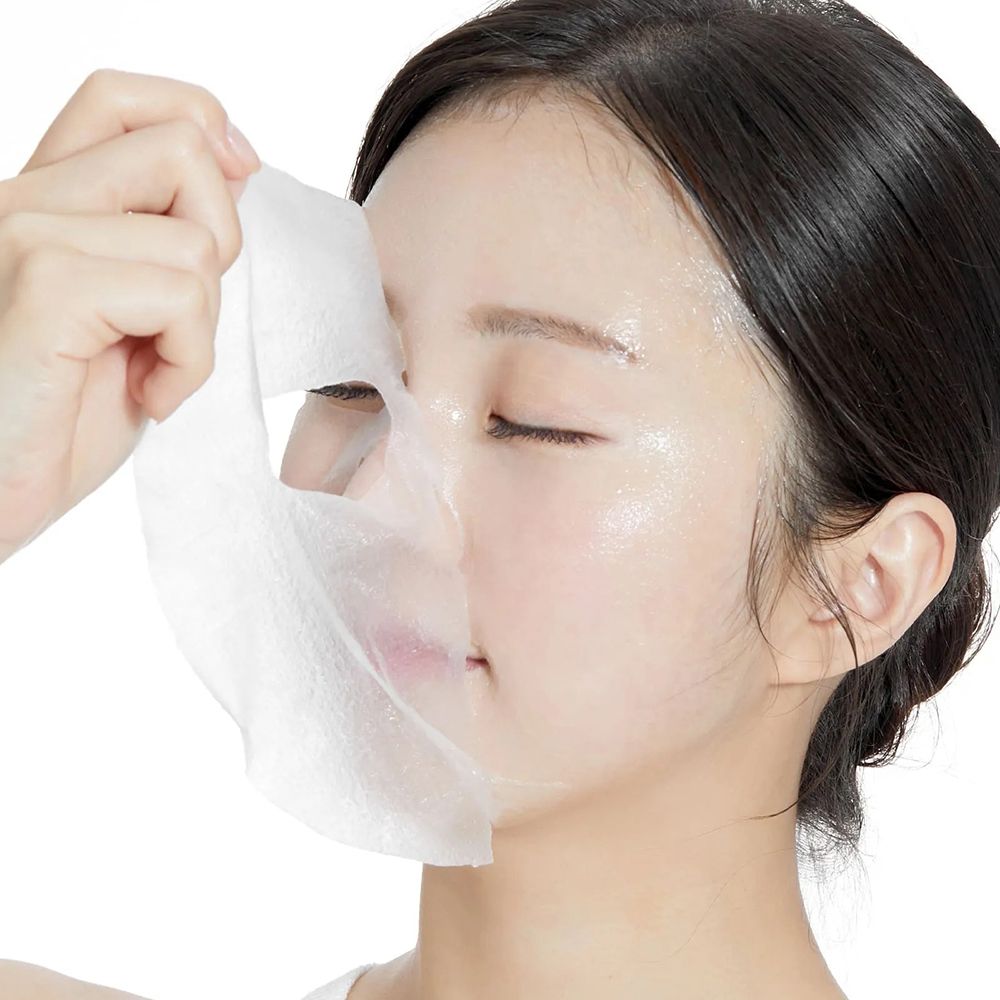 Applicazione di una maschera per il viso. Maschera bianca, donna che tiene la maschera. Prodotto per la cura della pelle.