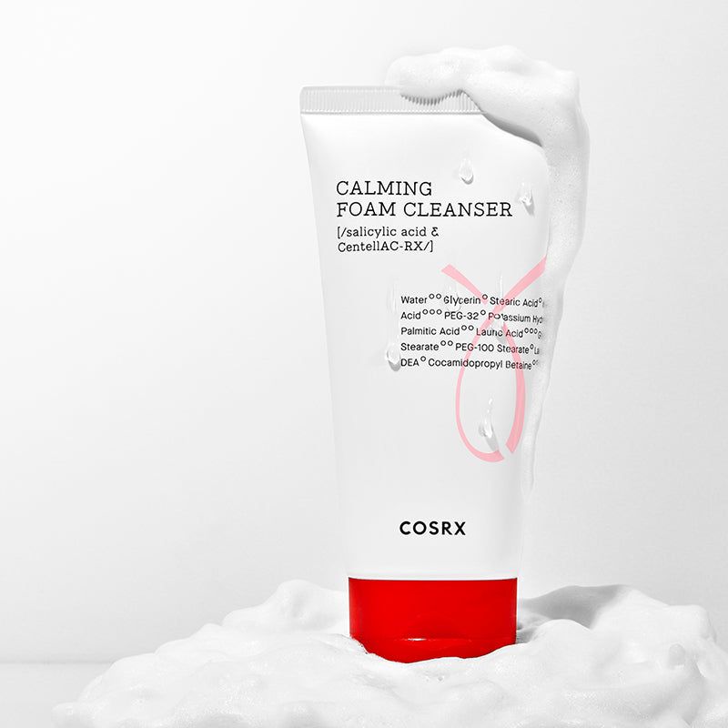 Tubo bianco con tappo rosso nella schiuma. Scritta: Calming Foam Cleanser, ingredienti. Marchio: COSRX.