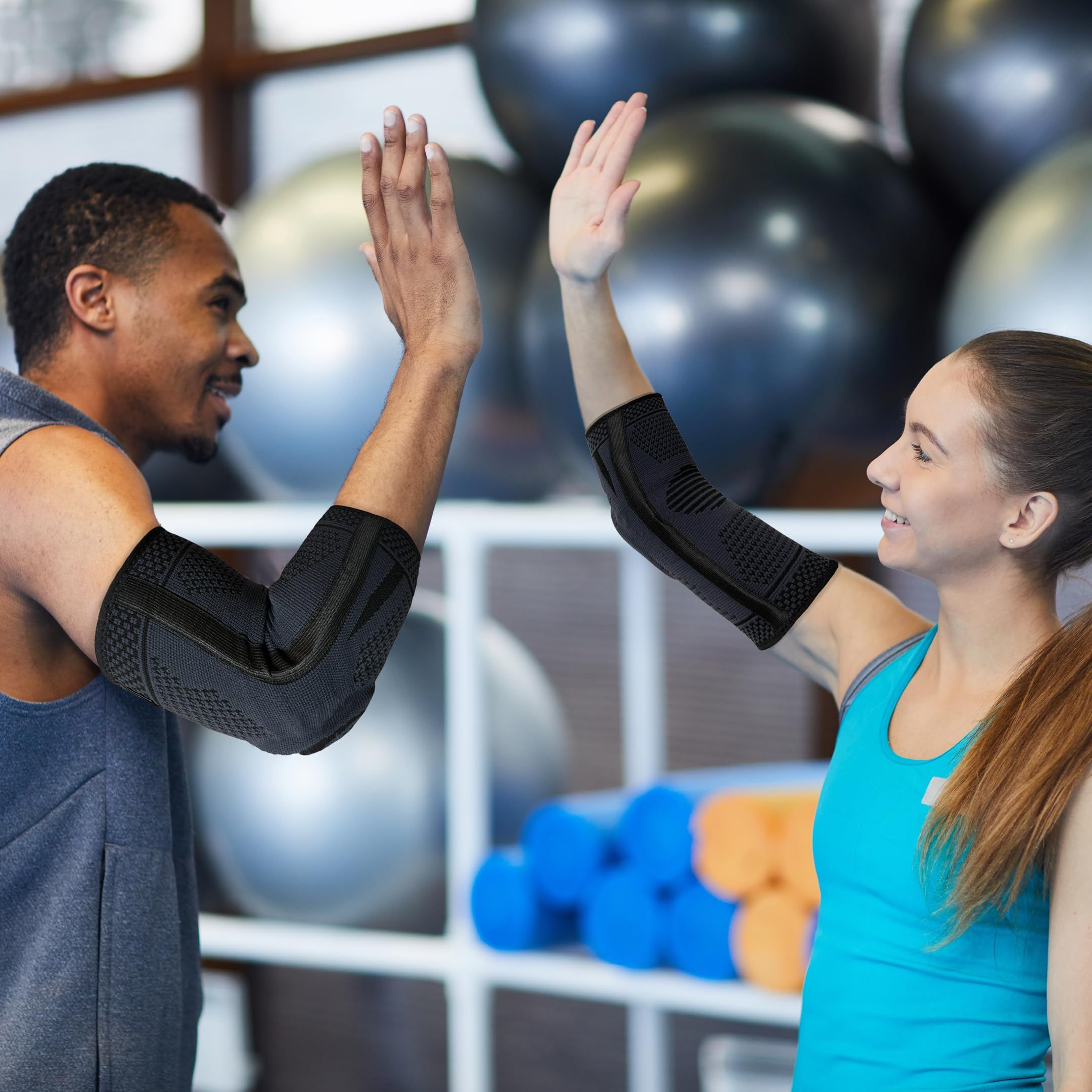 Due persone si danno il cinque. Entrambi indossano tutori per gomito neri. Sfondo della palestra.