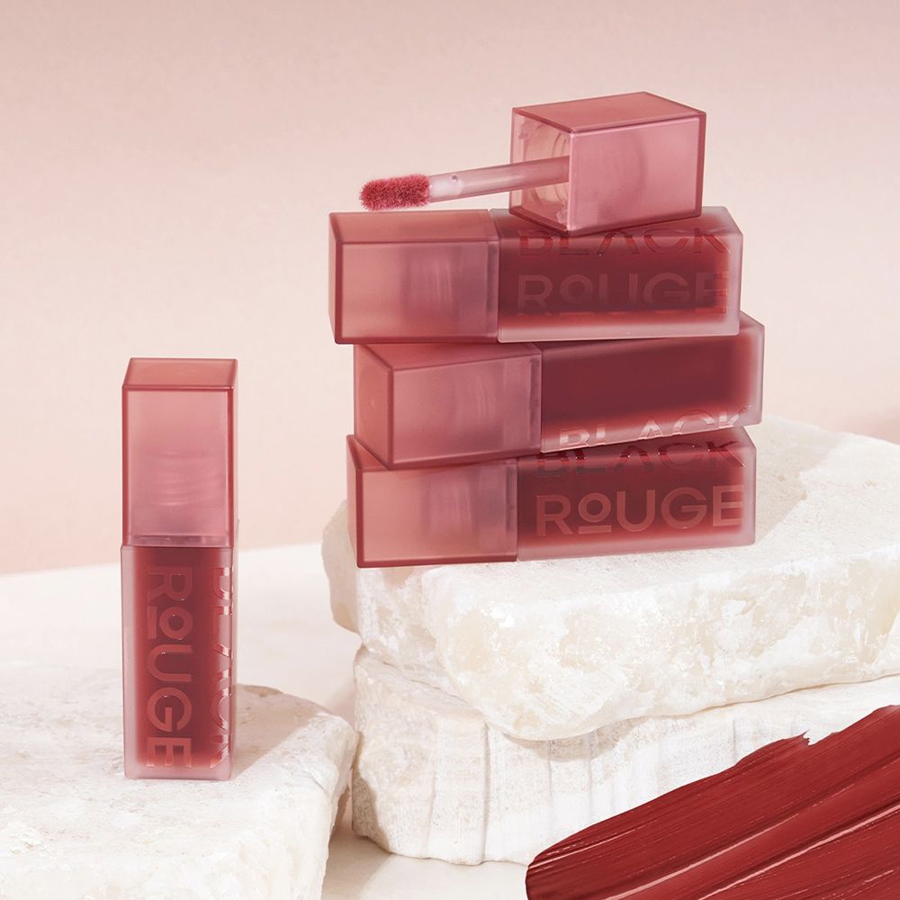 Diversi contenitori di lucidalabbra, impilati e singoli. Scritta "ROUGE".