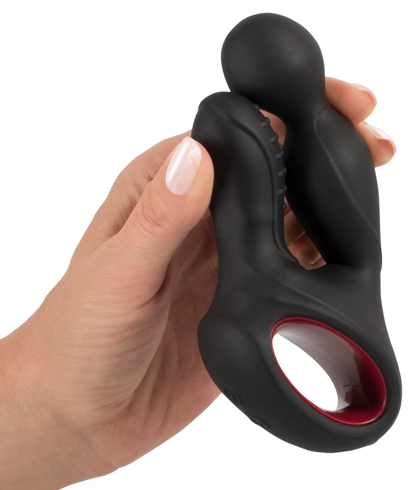 Prodotto nero in silicone con inserto rosso, tenuto da una mano. Forma allungata con estremità arrotondata e borchie.