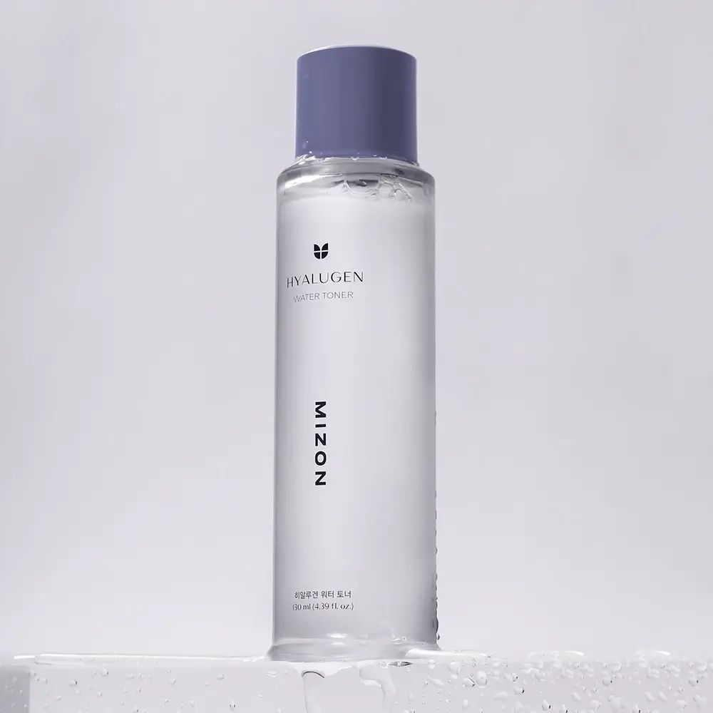 Flacone cilindrico trasparente di toner per il viso con tappo viola. Scritta: HYALUGEN WATER TONER, MIZON.