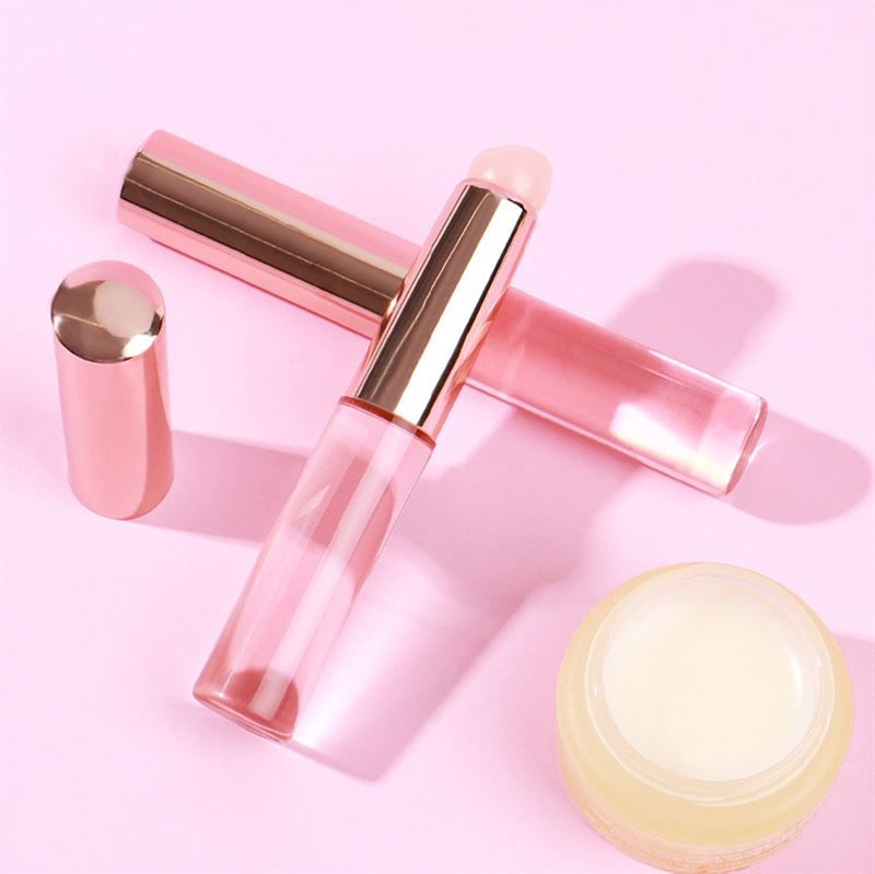 Due pennelli, un tappo e un vasetto su sfondo rosa. Pennelli con manico rosa e applicatore chiaro.
