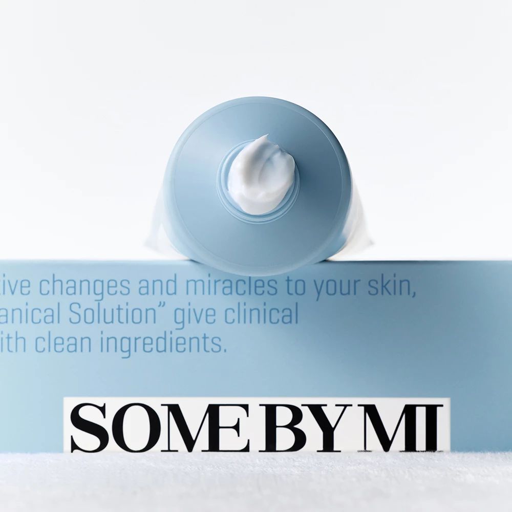 Tubo blu con crema bianca. Nome del prodotto e testo sul tubo. Sfondo bianco.