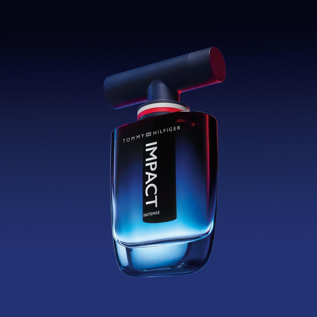 Flacone blu con etichetta nera IMPACT INTENSE. Tappo nero. Anello rosso e bianco sul collo. Sfondo blu.